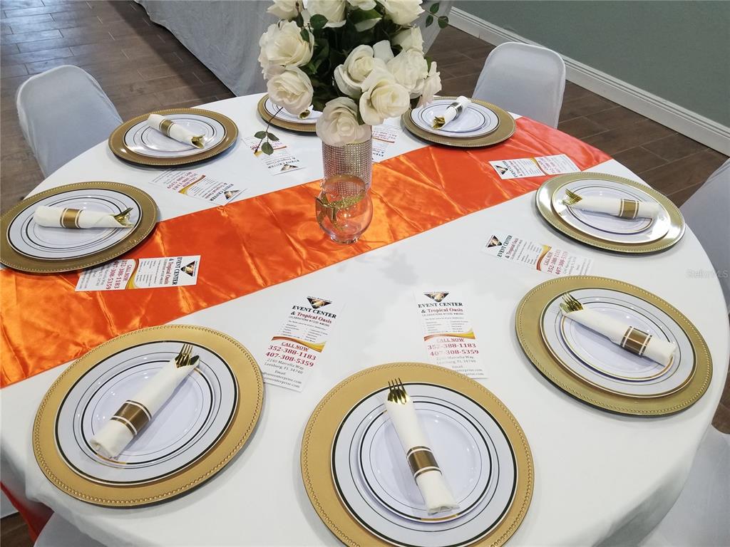 A round dining table is set with white plates, gold chargers, and an orange runner — 2240 MARCELLA WAY, LEESBURG, FL