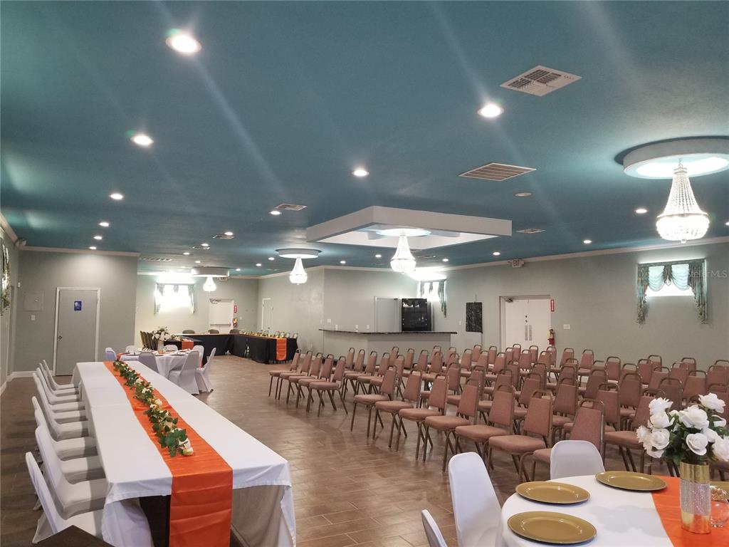 A large event hall features a teal ceiling, multiple chandeliers, tiled floors, and banquet seating — 2240 MARCELLA WAY, LEESBURG, FL