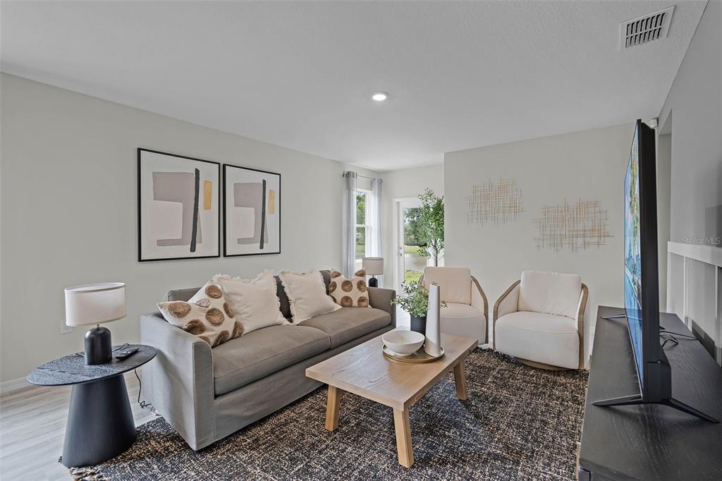 A living room features a gray sofa, two white armchairs, a coffee table, and wall art — 214 BULL FROG LANE, UMATILLA, FL