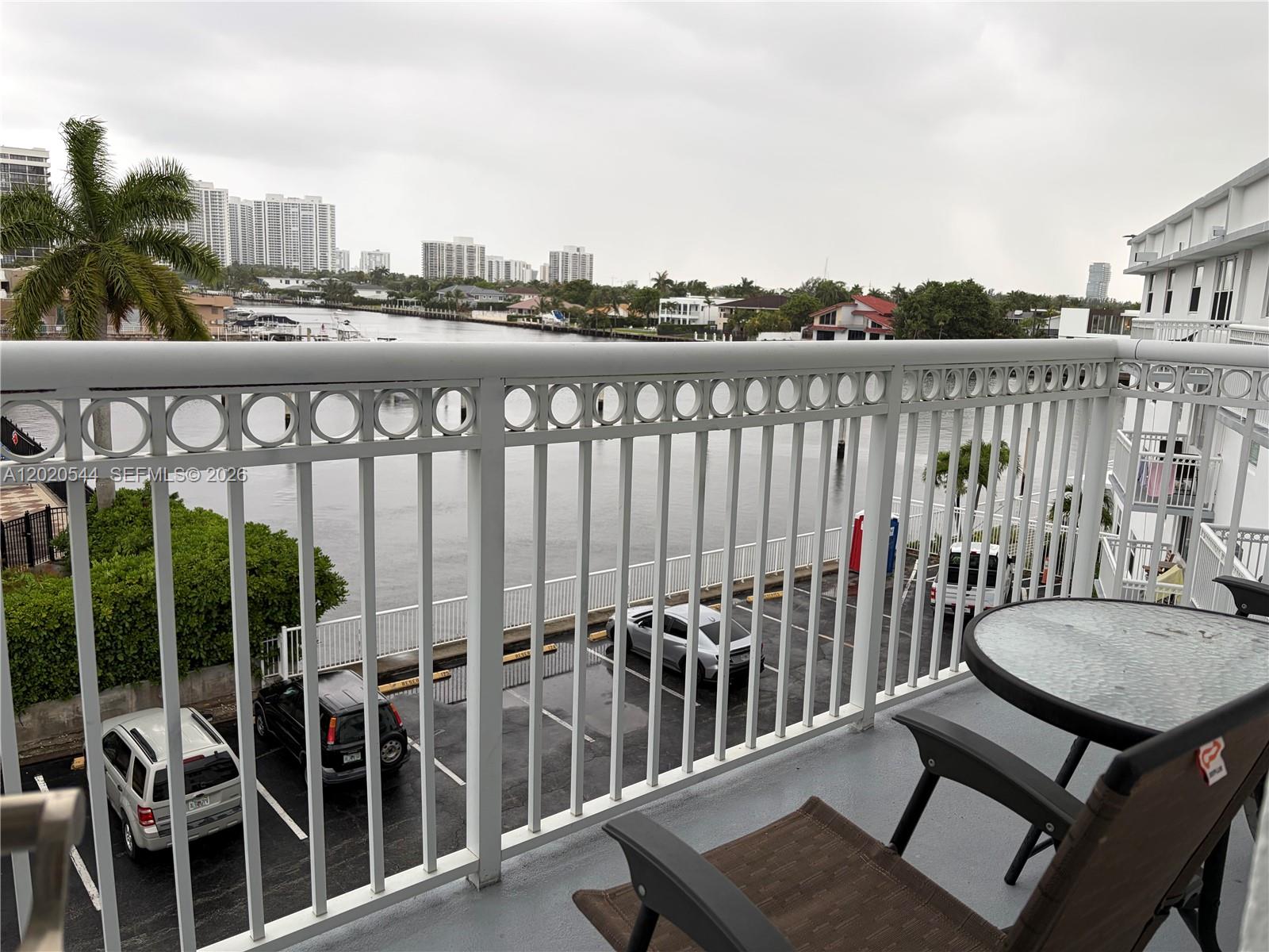 A balcony with a metal railing overlooks a parking lot and a waterway with buildings — 1913 S Ocean Dr # 427, Hallandale Beach FL 33009, HALLANDALE BEACH, FL
