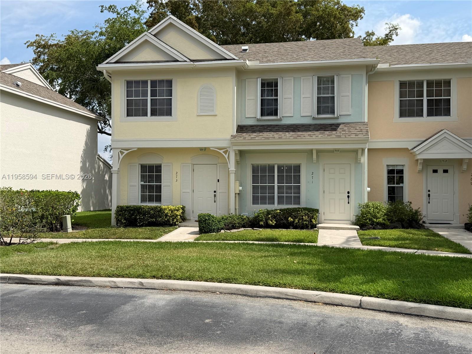 A row of multi-story townhouses features pastel-colored stucco siding and white trim — 271 Duval Ct, Weston FL 33326, WESTON, FL