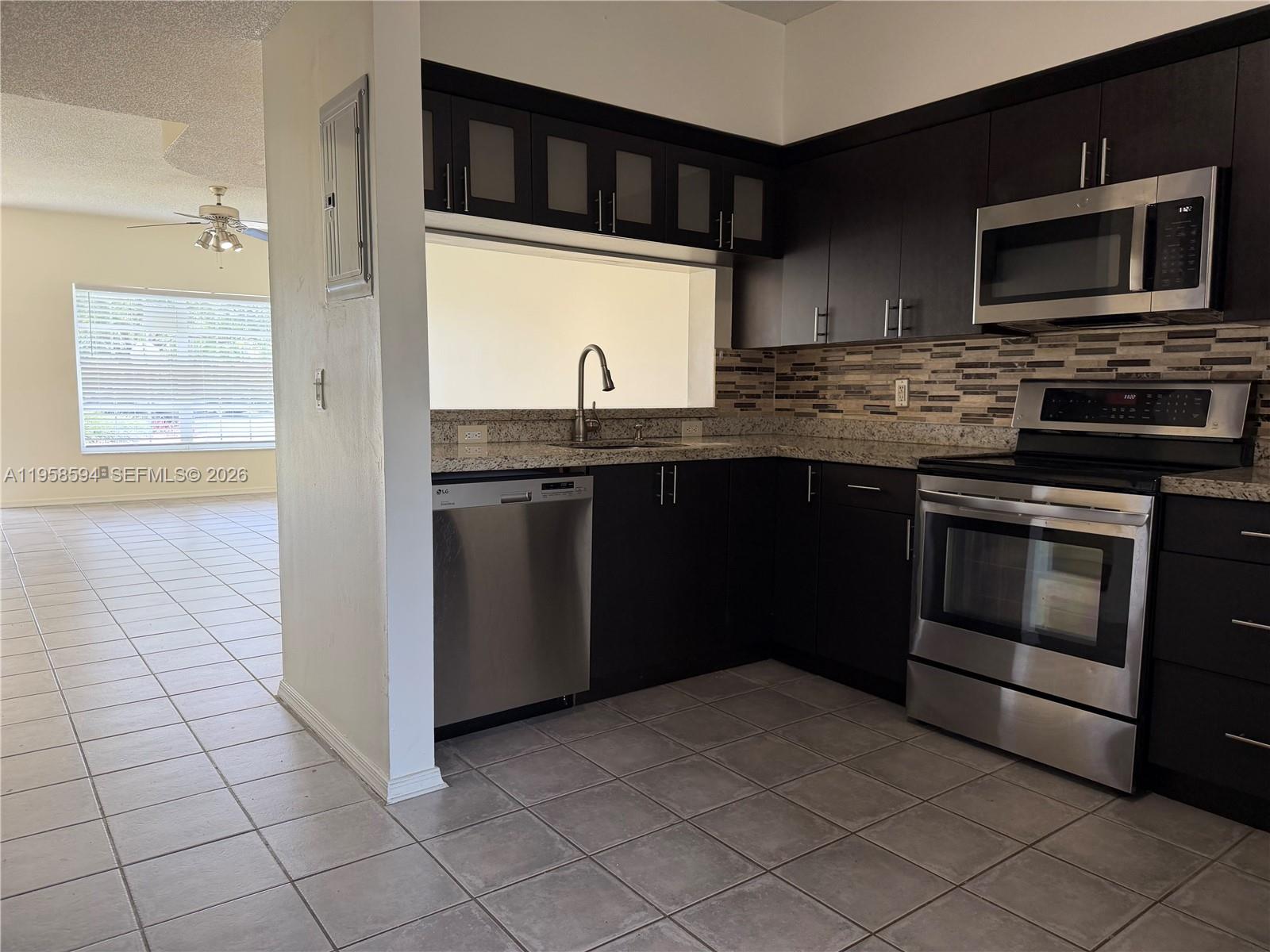 A kitchen features dark cabinets, stainless steel appliances, granite countertops, and a tiled floor — 271 Duval Ct, Weston FL 33326, WESTON, FL