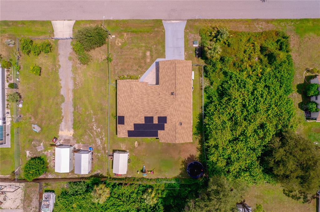 An aerial view shows a house with solar panels on its roof and a large backyard — 1157 BEAUMONT AVENUE, PORT CHARLOTTE, FL