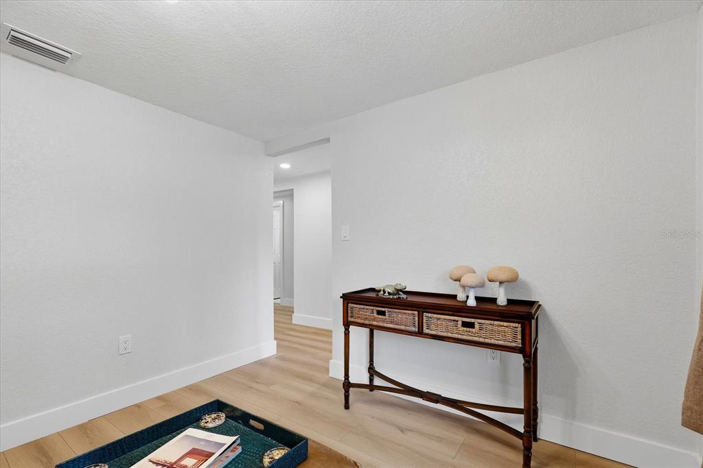 A room with light wood flooring, white walls, and a wooden console table — 12021 107TH COURT, LARGO, FL