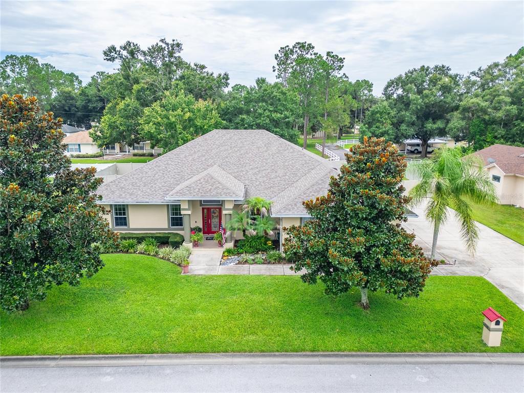 An aerial view of a single-story house with a red front door and large trees — 170 OLD NICHOLS CIRCLE, AUBURNDALE, FL