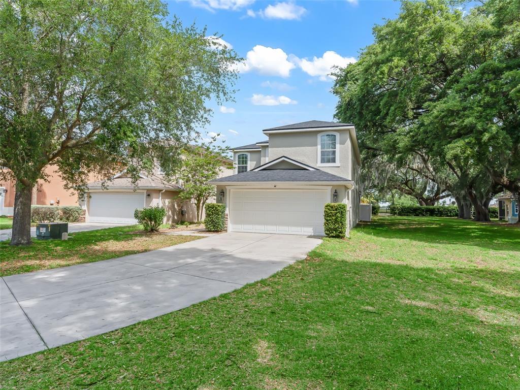 A two-story house with a white garage door and a concrete driveway sits on grass — 4942 NE 123RD LANE, OXFORD, FL