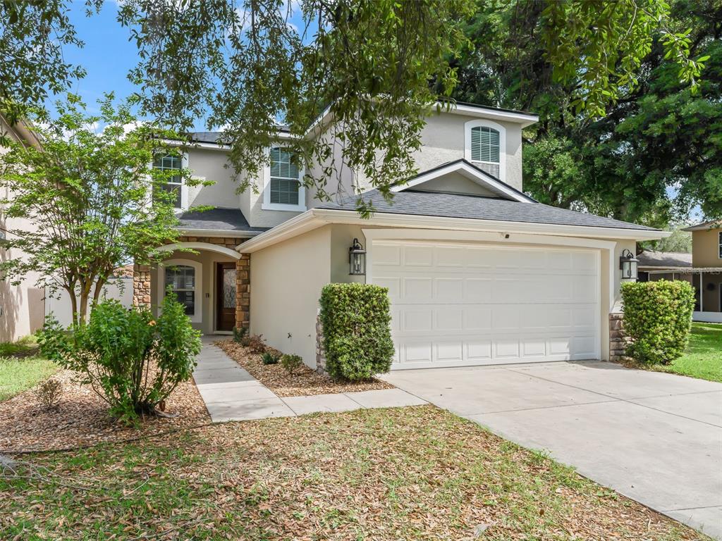A two-story house with a beige stucco exterior, a two-car garage, and a stone entryway — 4942 NE 123RD LANE, OXFORD, FL