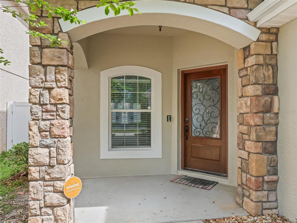 A front entryway features a wooden door with decorative glass, a window, and stone pillars — 4942 NE 123RD LANE, OXFORD, FL