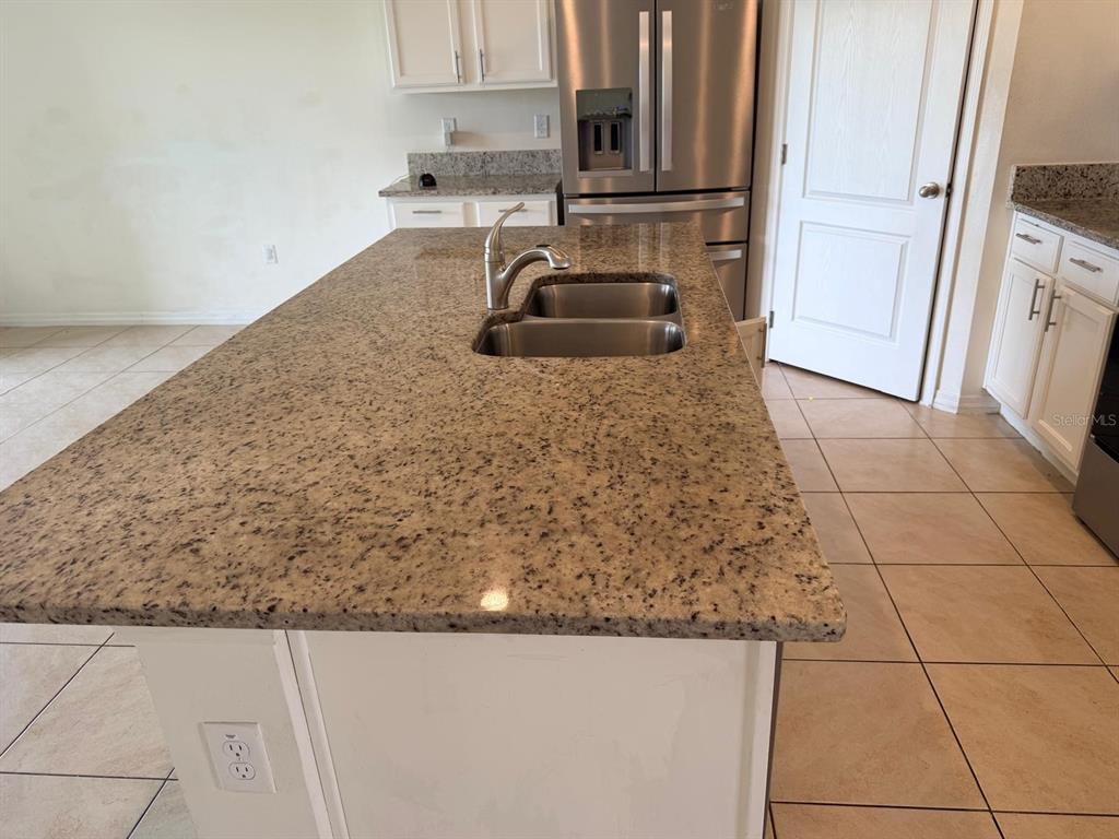 A kitchen island with a granite countertop and stainless steel sink sits in a kitchen — 1229 RED HILL ROAD, DAVENPORT, FL