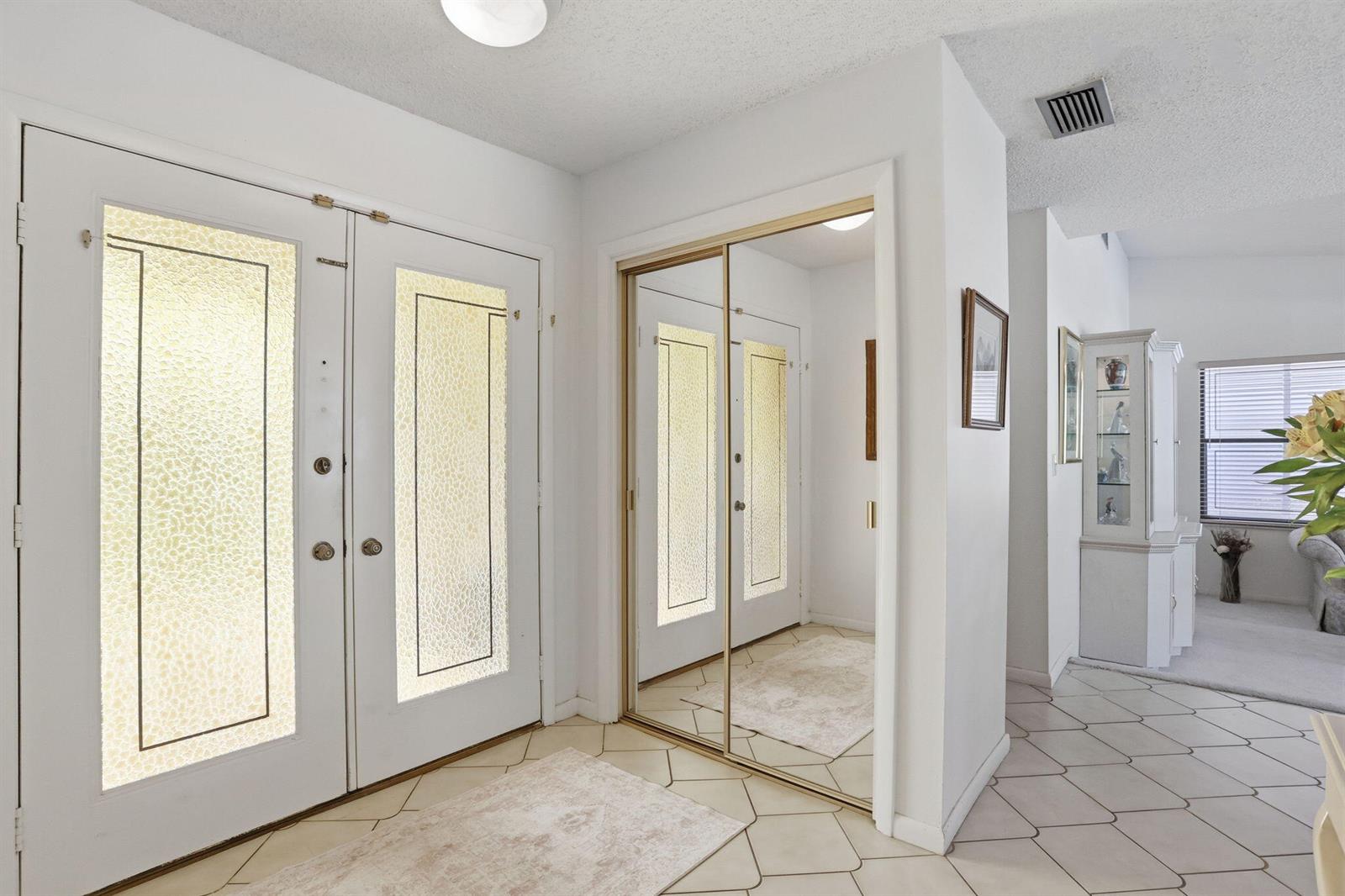 An entryway features white double doors, a mirrored closet, and light-colored tile flooring — 4281 Sugar Pine Drive, Boca Raton FL 33487, BOCA RATON, FL