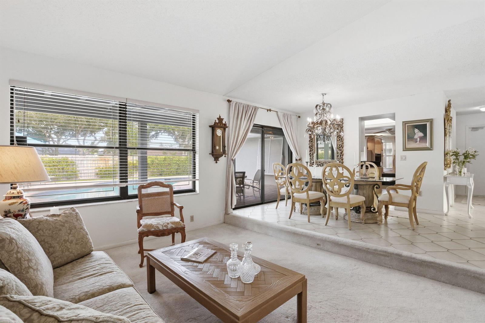 A living and dining area features carpeted and tiled floors, a chandelier, and sliding doors — 4281 Sugar Pine Drive, Boca Raton FL 33487, BOCA RATON, FL