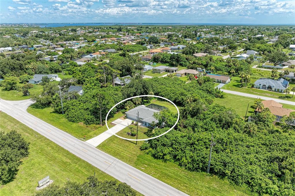An aerial view shows a single-story house with a screened pool enclosure surrounded by trees — 18565 EDGEWATER DRIVE, PORT CHARLOTTE, FL