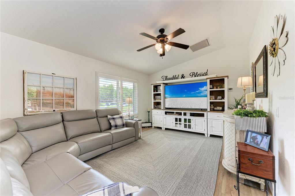 A living room features a gray sectional sofa, a large television, and white built-in cabinetry — 18565 EDGEWATER DRIVE, PORT CHARLOTTE, FL