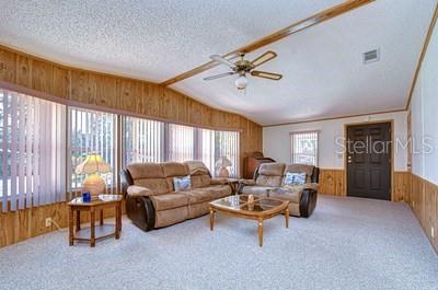 A living room features wood-paneled walls, a ceiling fan, and two brown sofas — 35909 BUENO DRIVE, ZEPHYRHILLS, FL