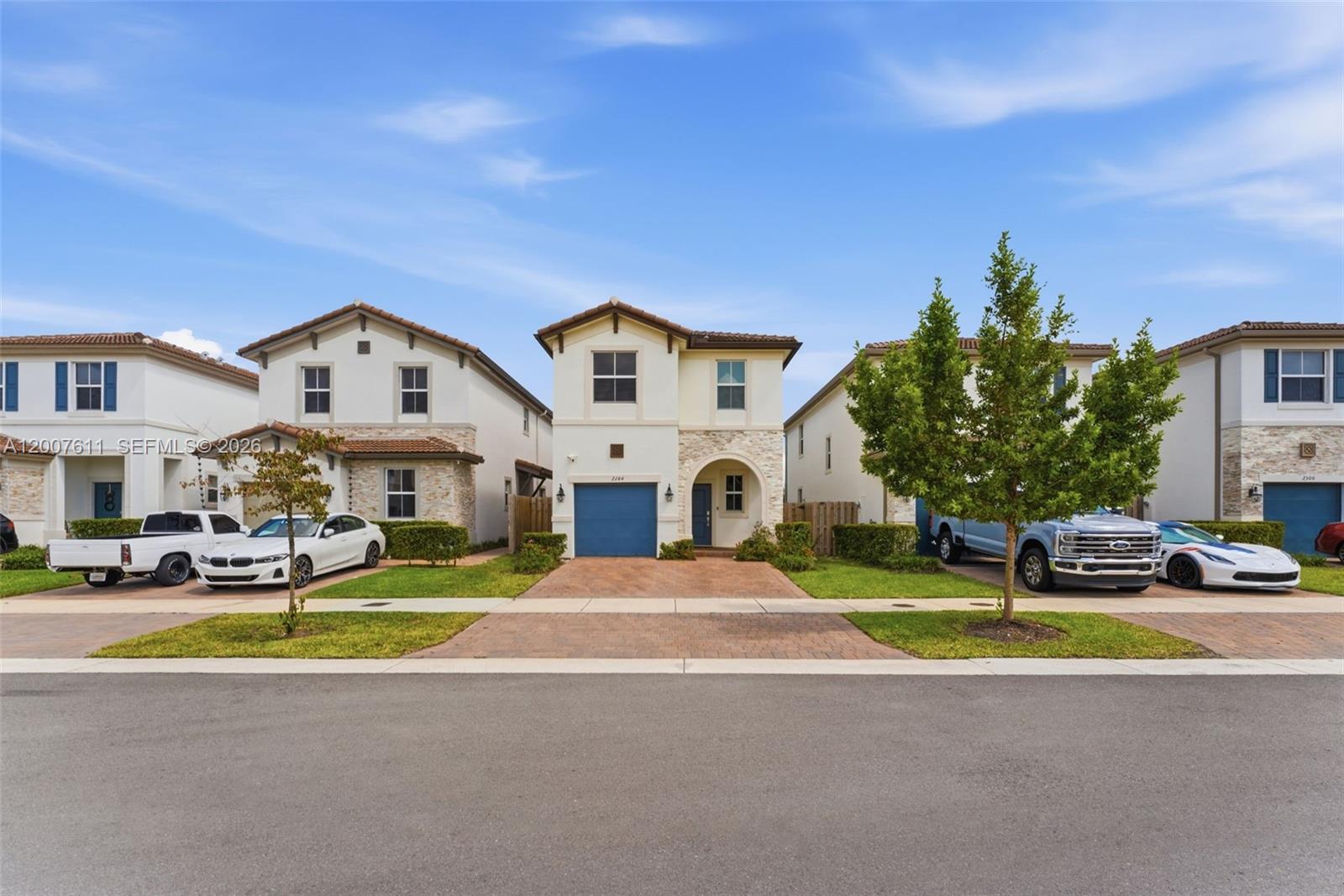 A row of three two-story suburban houses with driveways and parked vehicles under a blue sky — 2284 NW 130th St # 0, Miami FL 33167, MIAMI, FL