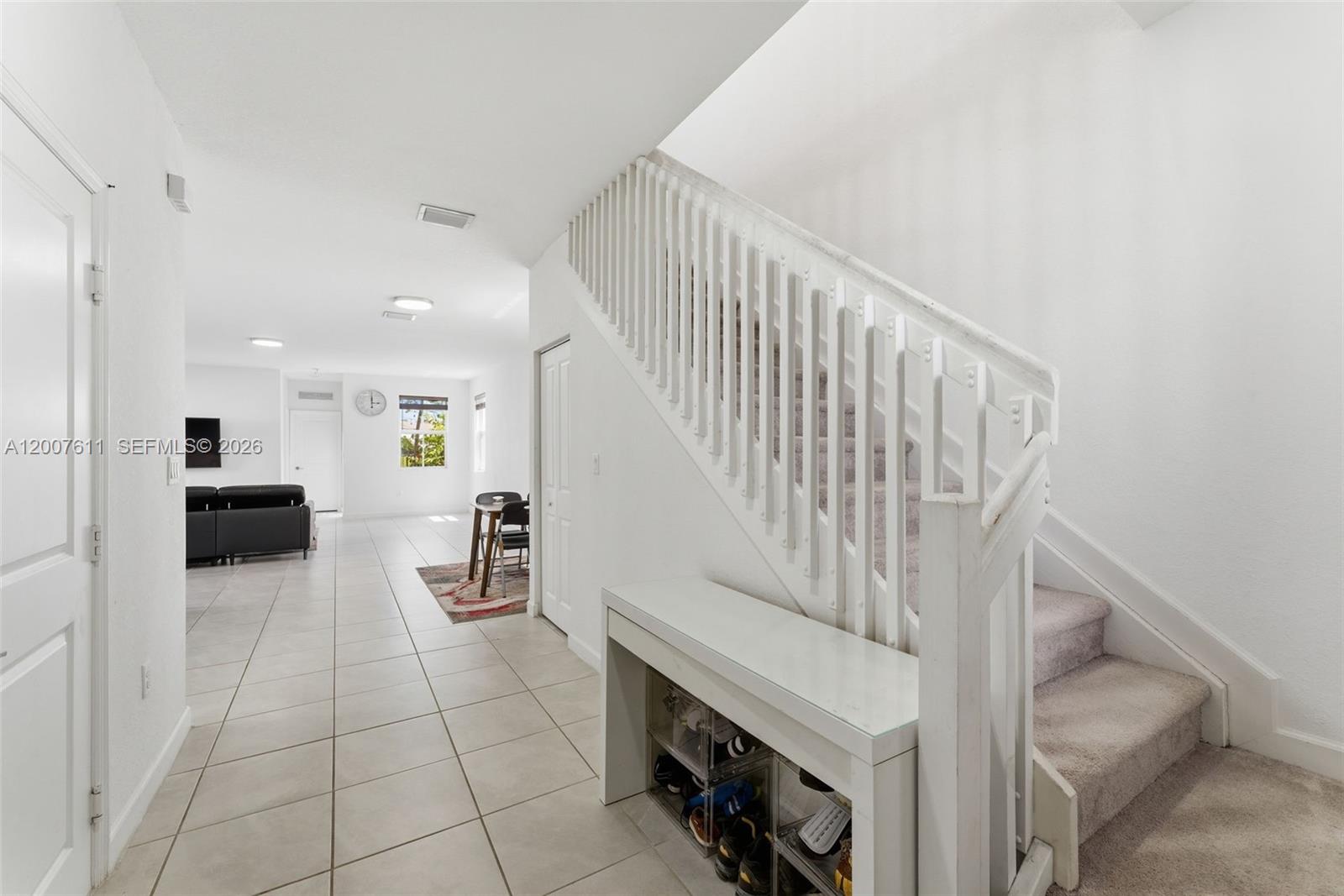 A white staircase with a shoe storage console sits in a tiled entryway — 2284 NW 130th St # 0, Miami FL 33167, MIAMI, FL