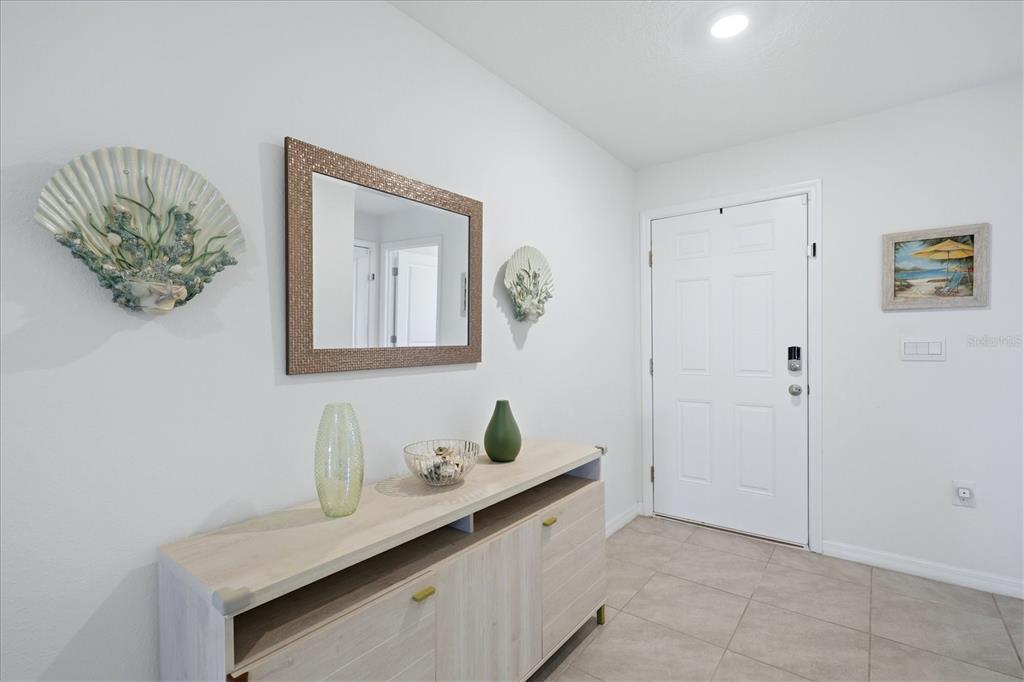 A bright entryway features a light wood console table, a mirror, and coastal wall decor — 5051 GRANITE DUST PLACE, PALMETTO, FL