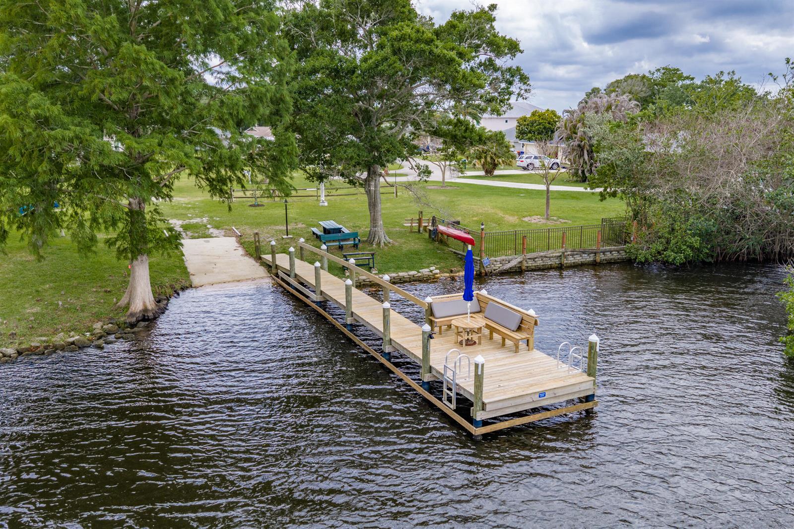 An aerial view shows a wooden dock extending into a river from a grassy yard — SEBASTIAN, FL
