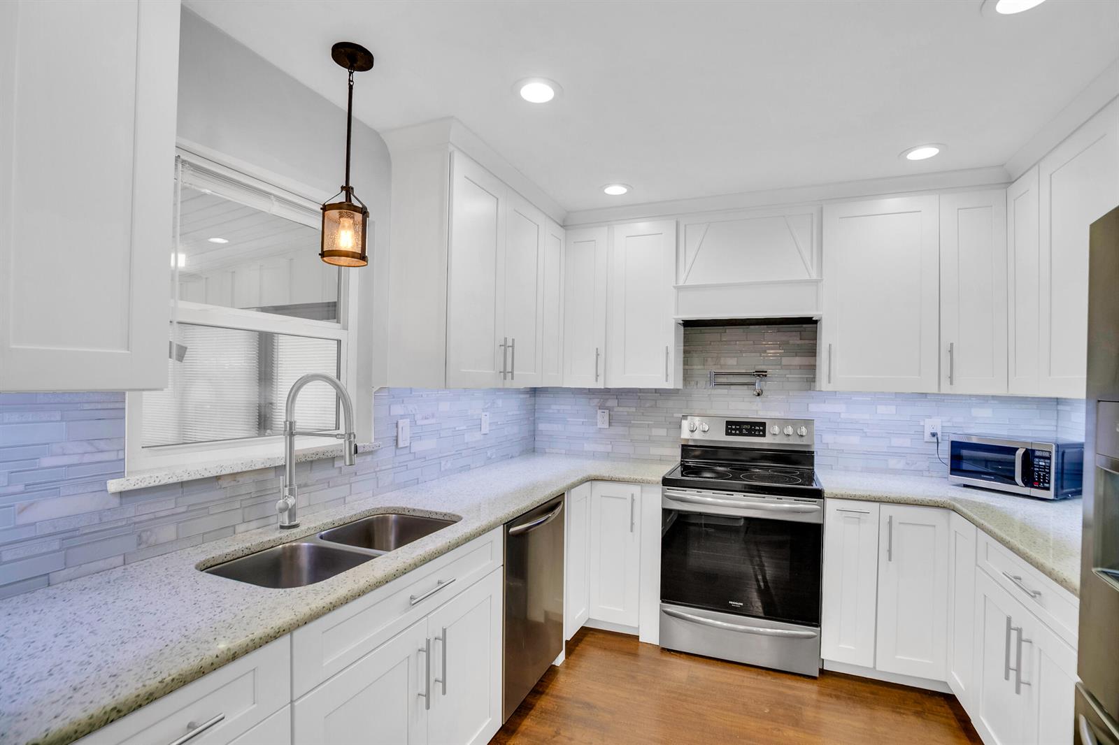A kitchen with white cabinets, stainless steel appliances, granite countertops, and a tiled backsplash — SEBASTIAN, FL