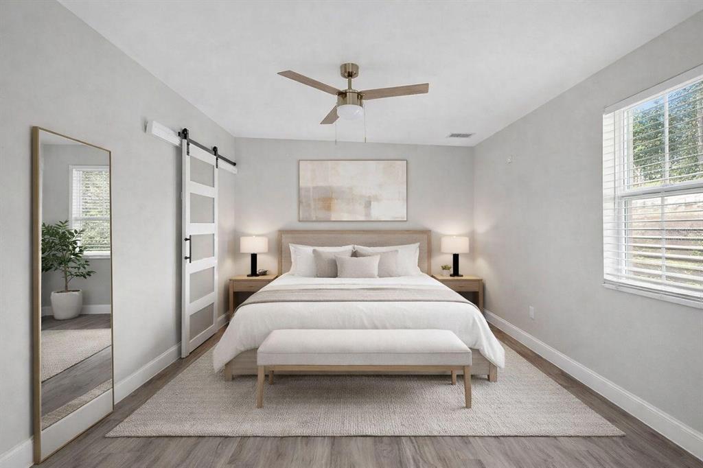 A bedroom features a bed with a bench, a barn door, and a full-length mirror — 34796 GARDENIA WAY, DADE CITY, FL