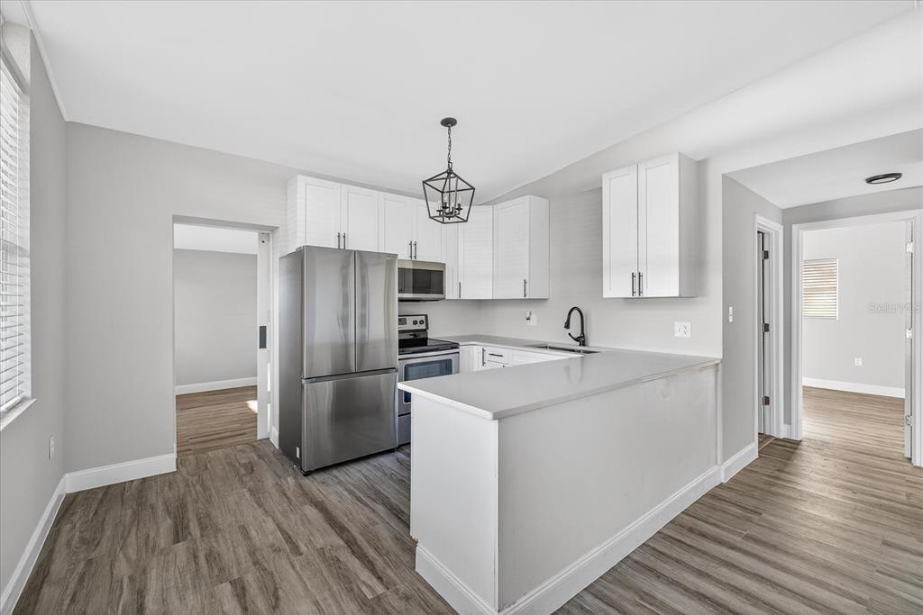 A modern kitchen features white cabinets, stainless steel appliances, and a peninsula counter — 34796 GARDENIA WAY, DADE CITY, FL