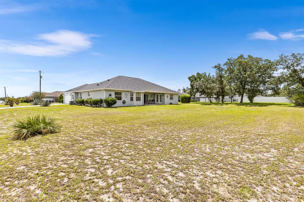 A single-story house with a gray roof sits on a large, grassy, sandy lot — 10360 SW 48TH AVENUE, OCALA, FL