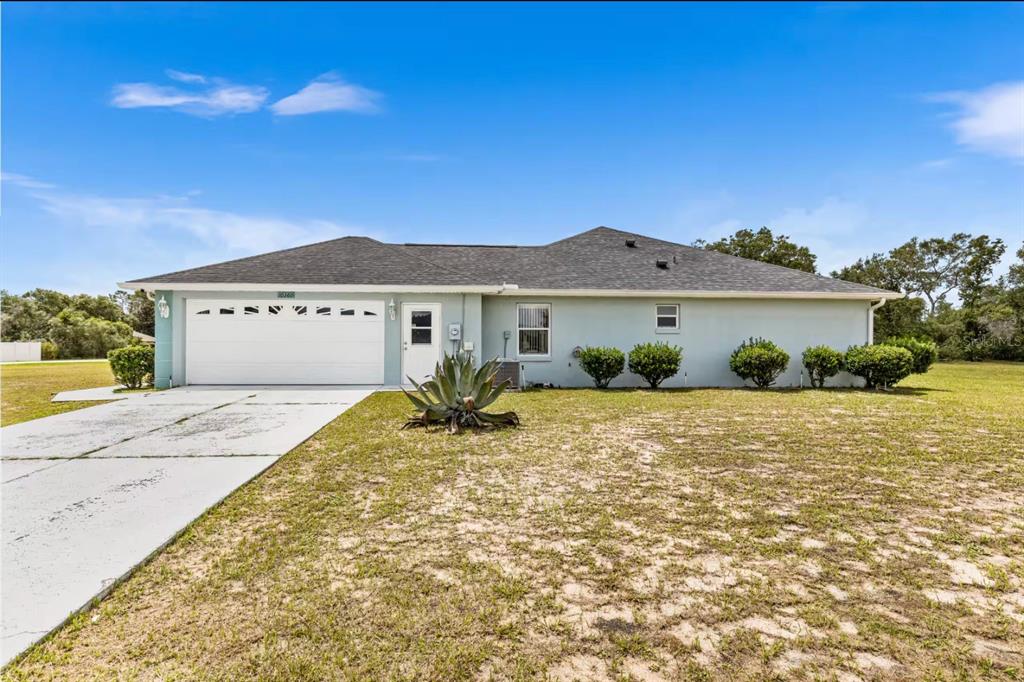 A single-story house with a white garage door, light blue exterior, and a concrete driveway — 10360 SW 48TH AVENUE, OCALA, FL