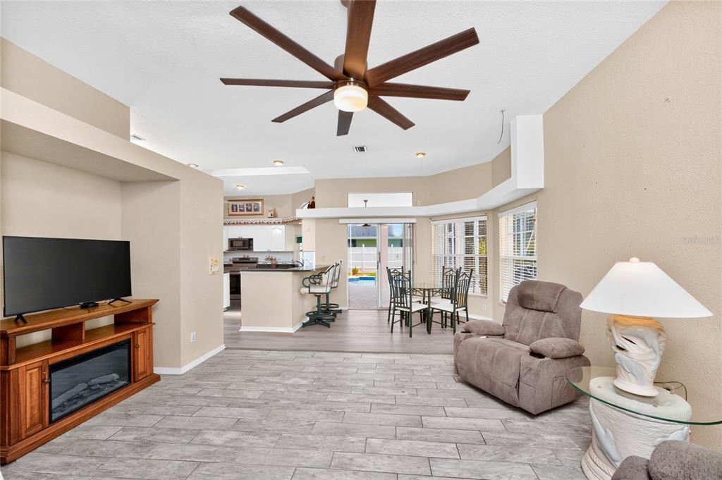 A living room with tile flooring, a ceiling fan, a fireplace, and an adjacent kitchen — 417 SCARLET SAGE, PUNTA GORDA, FL