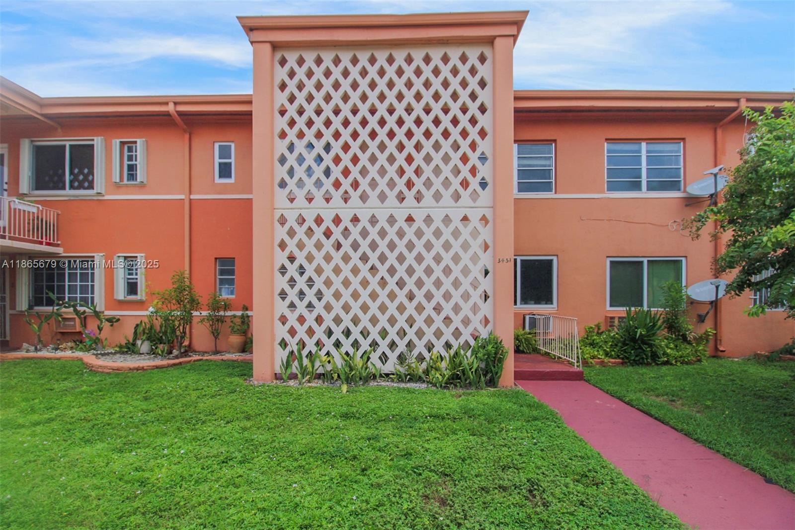 The exterior of a two-story peach-colored apartment building features a central white lattice screen — 3451 SW 11th St # 8A, Miami FL 33135, MIAMI, FL