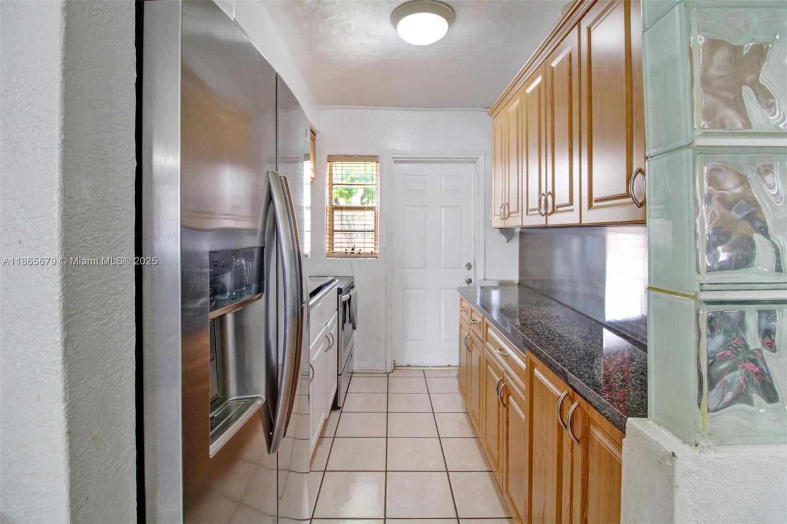 A galley kitchen features stainless steel appliances, wood cabinets, and dark granite countertops — 3451 SW 11th St # 8A, Miami FL 33135, MIAMI, FL