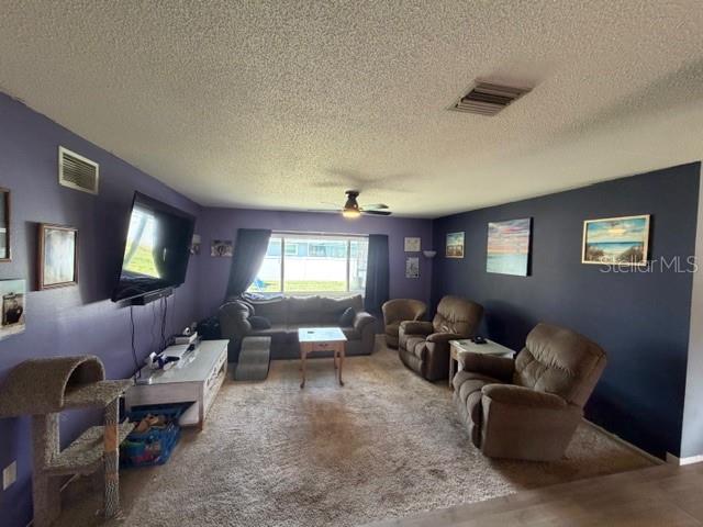 A living room features purple and dark blue walls, carpeted flooring, and several recliner chairs — 1381 EAGLE STREET, PORT CHARLOTTE, FL