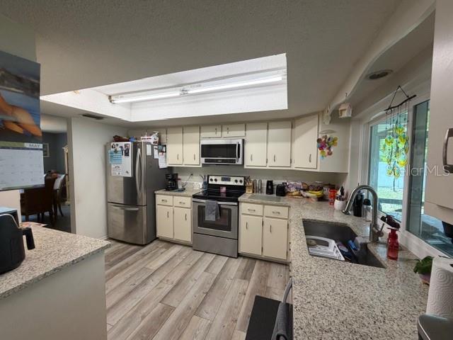 A kitchen features light-colored cabinets, granite countertops, stainless steel appliances, and wood-look flooring — 1381 EAGLE STREET, PORT CHARLOTTE, FL