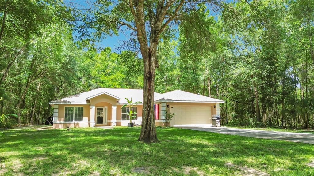 A single-story house with a beige exterior, a two-car garage, and a large front yard — 2226 SW ALGIERS COURT, DUNNELLON, FL