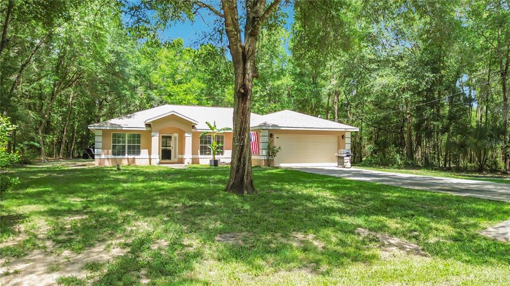 A single-story house with a beige exterior, a two-car garage, and a large front yard — 2226 SW ALGIERS COURT, DUNNELLON, FL