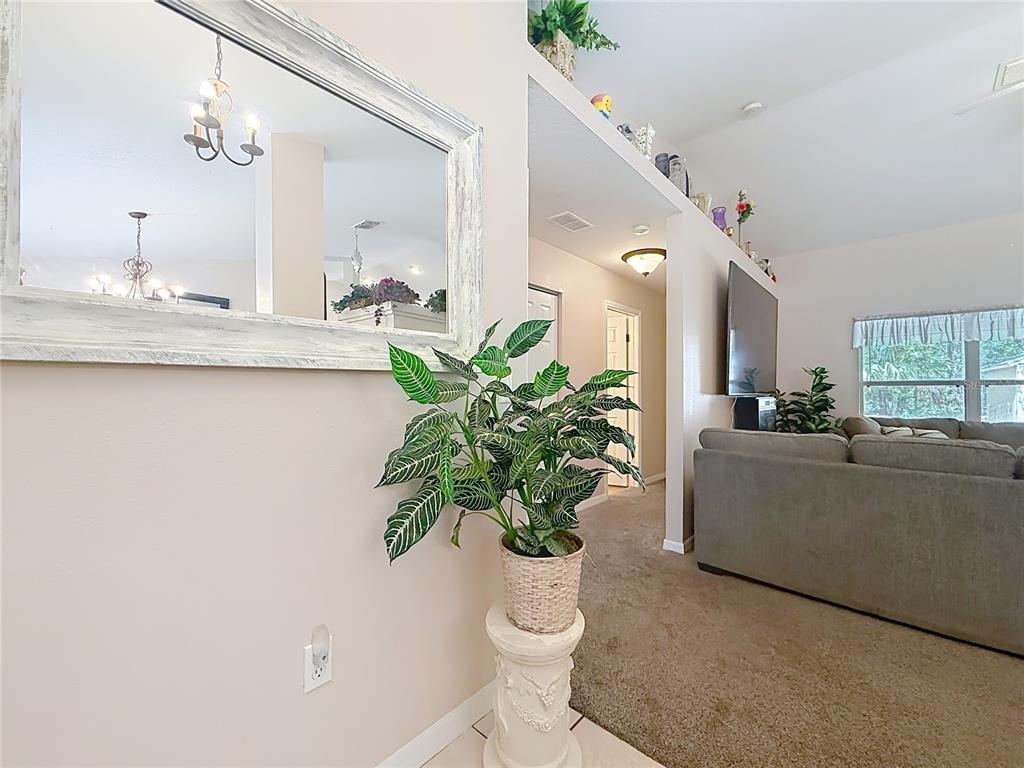 A potted plant sits on a pedestal in a living room with a wall mirror — 2226 SW ALGIERS COURT, DUNNELLON, FL