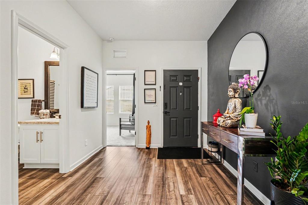 An entryway features wood-look flooring, a dark accent wall, a console table, and a mirror — 35739 BUTTONWEED TRAIL, ZEPHYRHILLS, FL