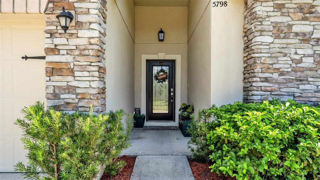 The front entrance features a black door with a glass insert and stone veneer accents — 5798 DORNICH DRIVE, AUBURNDALE, FL