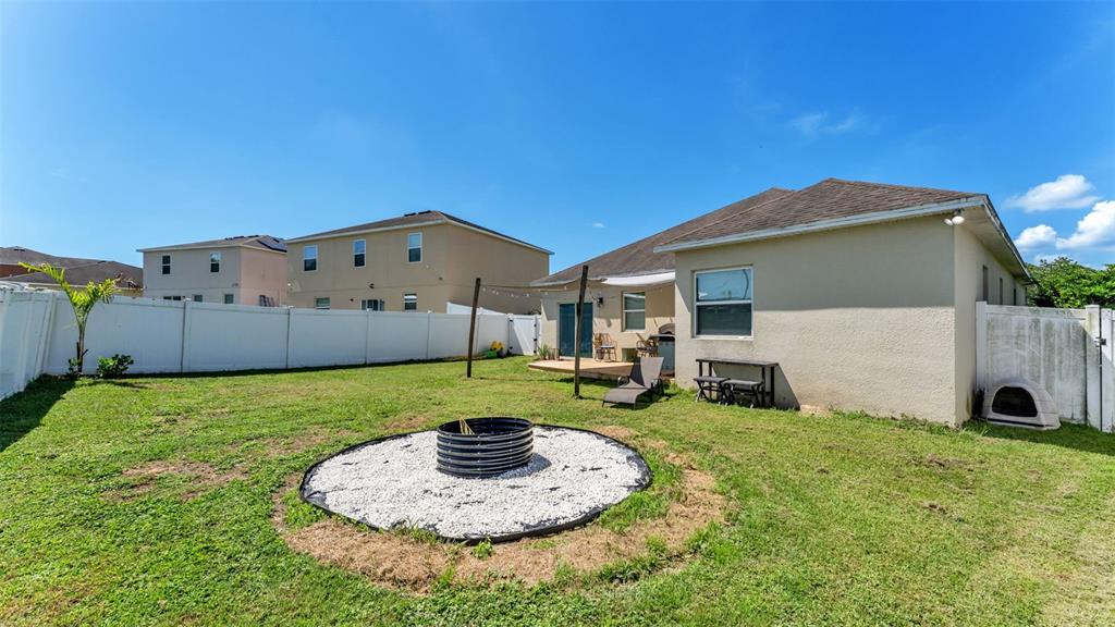 A backyard features a circular gravel fire pit area, a patio, and a white fence — 5798 DORNICH DRIVE, AUBURNDALE, FL