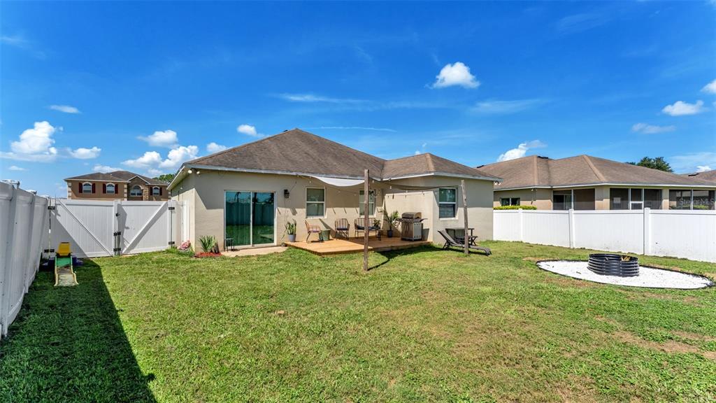The backyard features a wooden deck, a fire pit, and a white vinyl privacy fence — 5798 DORNICH DRIVE, AUBURNDALE, FL