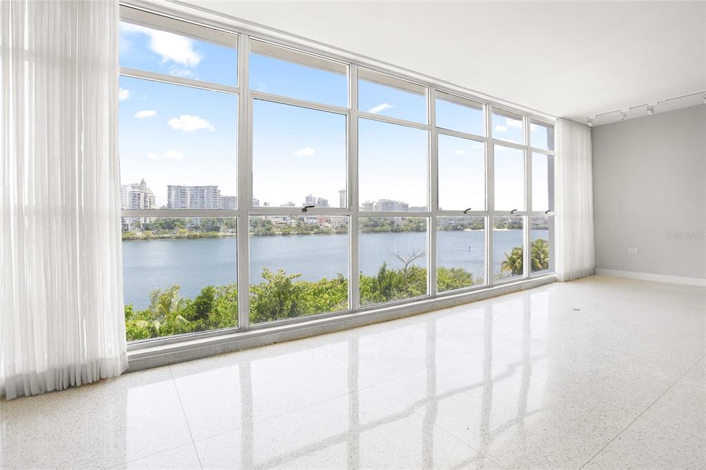A bright, empty room with white tile floors and a large window wall overlooking water — 860 ASHFORD AVENUE #5C UNIT #1 UNIT 1, SAN JUAN, PR