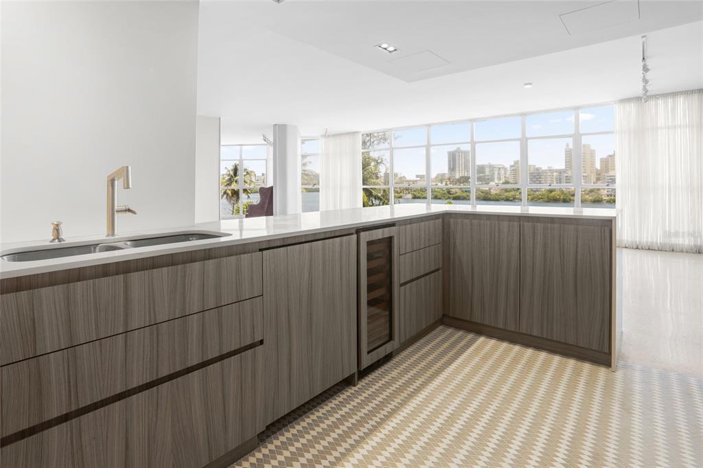 A modern kitchen features wood-grain cabinetry, a wine cooler, and large windows overlooking a city — 860 ASHFORD AVENUE #5C UNIT #1 UNIT 1, SAN JUAN, PR