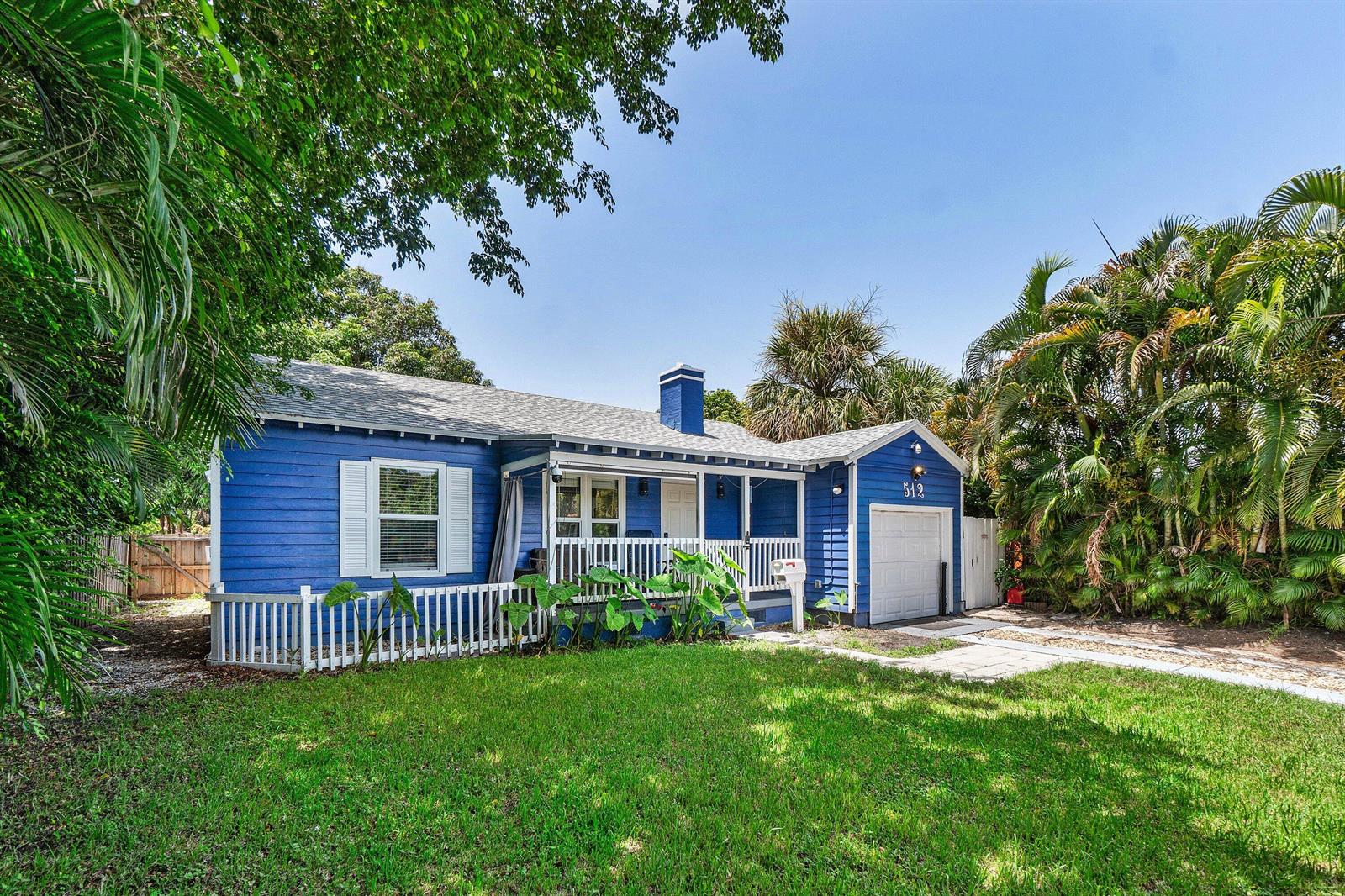 A blue, single-story house with a front porch, white trim, and an attached garage — 512 36th Street, West Palm Beach FL 33407, WEST PALM BEACH, FL