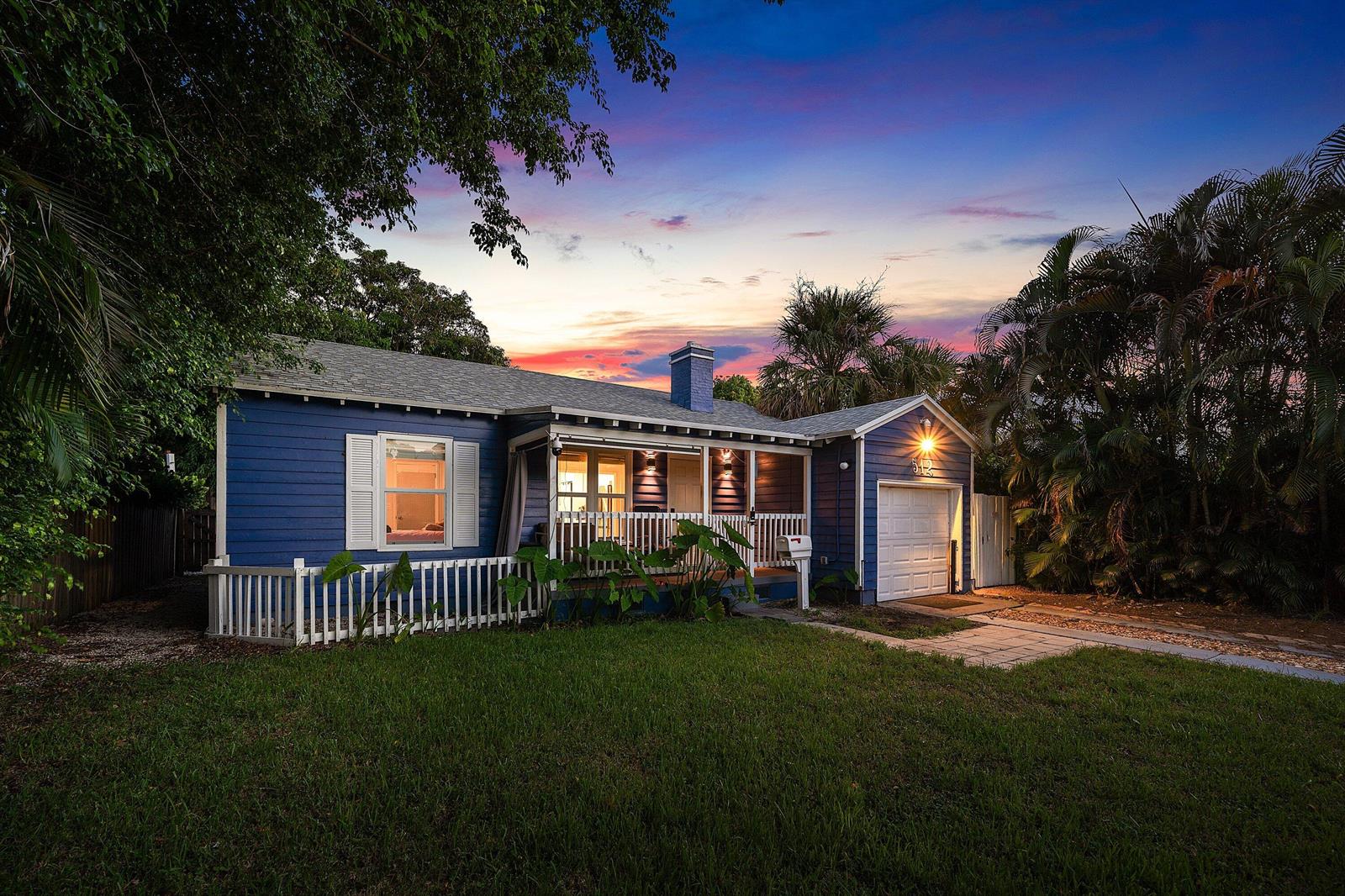 A blue single-story house with a front porch, white railings, and an attached garage — 512 36th Street, West Palm Beach FL 33407, WEST PALM BEACH, FL