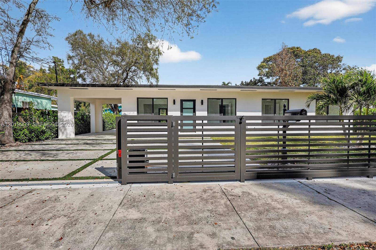 A white single-story house features a dark horizontal slat fence and a concrete driveway — 53 NW 68th St, Miami FL 33150, MIAMI, FL
