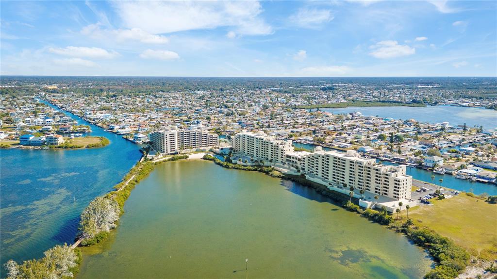 An aerial view shows two large waterfront apartment buildings surrounded by a residential coastal community — 6009 SEA RANCH DRIVE UNIT 307, HUDSON, FL