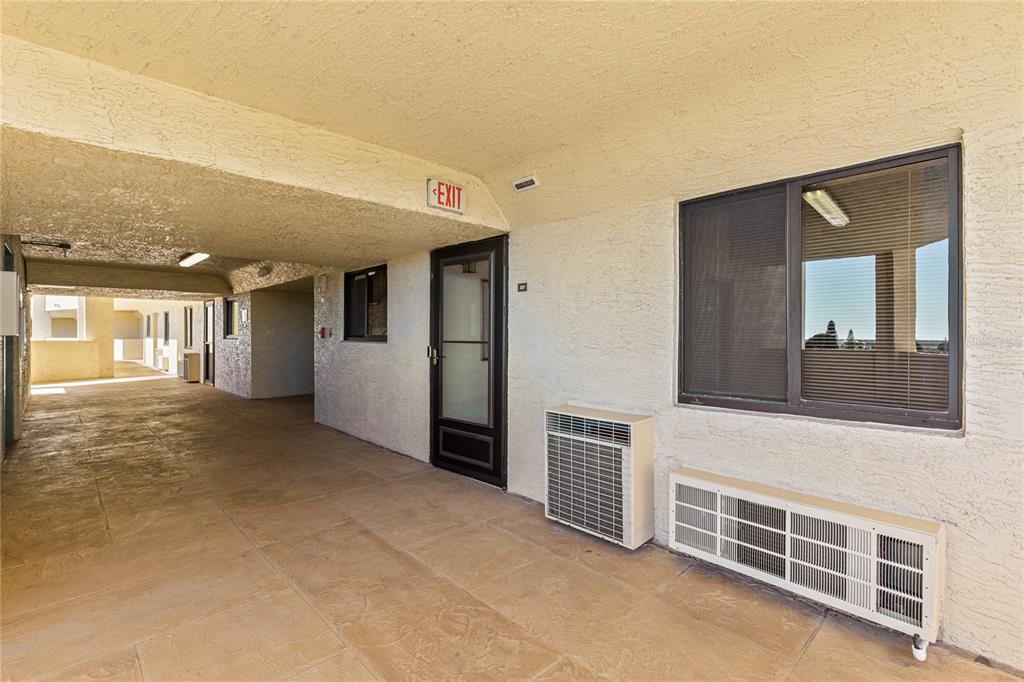An outdoor walkway leads to a building entrance with a window and two air-conditioning units — 6009 SEA RANCH DRIVE UNIT 307, HUDSON, FL
