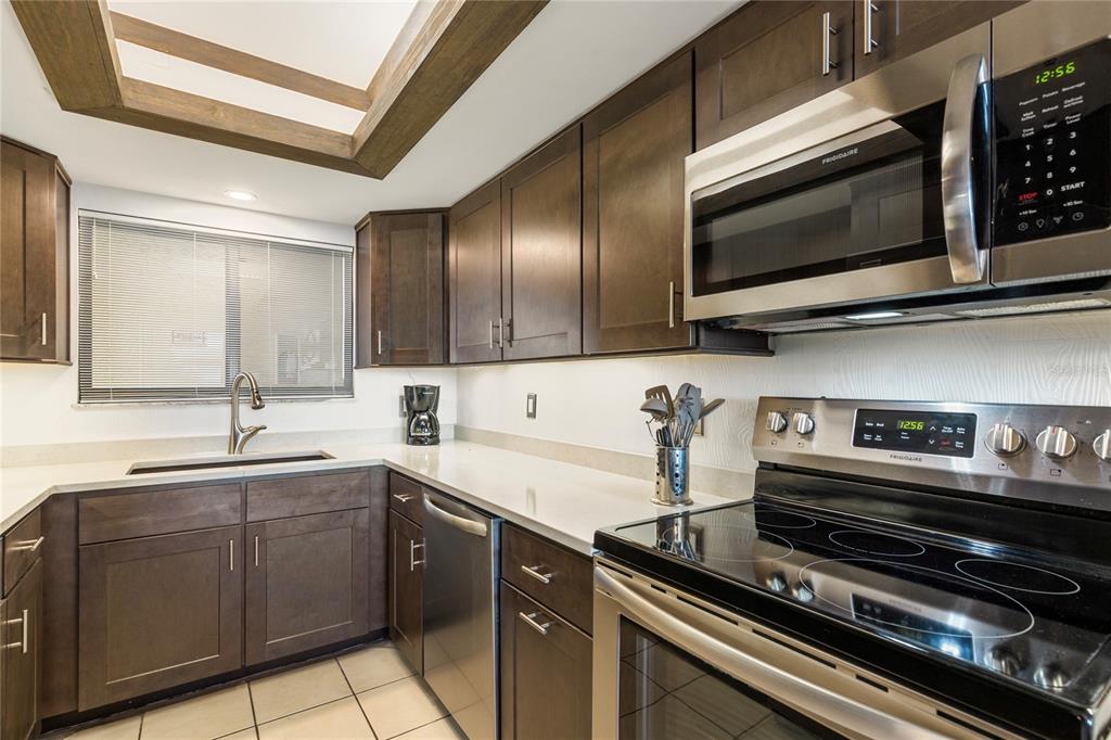 A kitchen features dark wood cabinets, stainless steel appliances, and white countertops — 6009 SEA RANCH DRIVE UNIT 307, HUDSON, FL