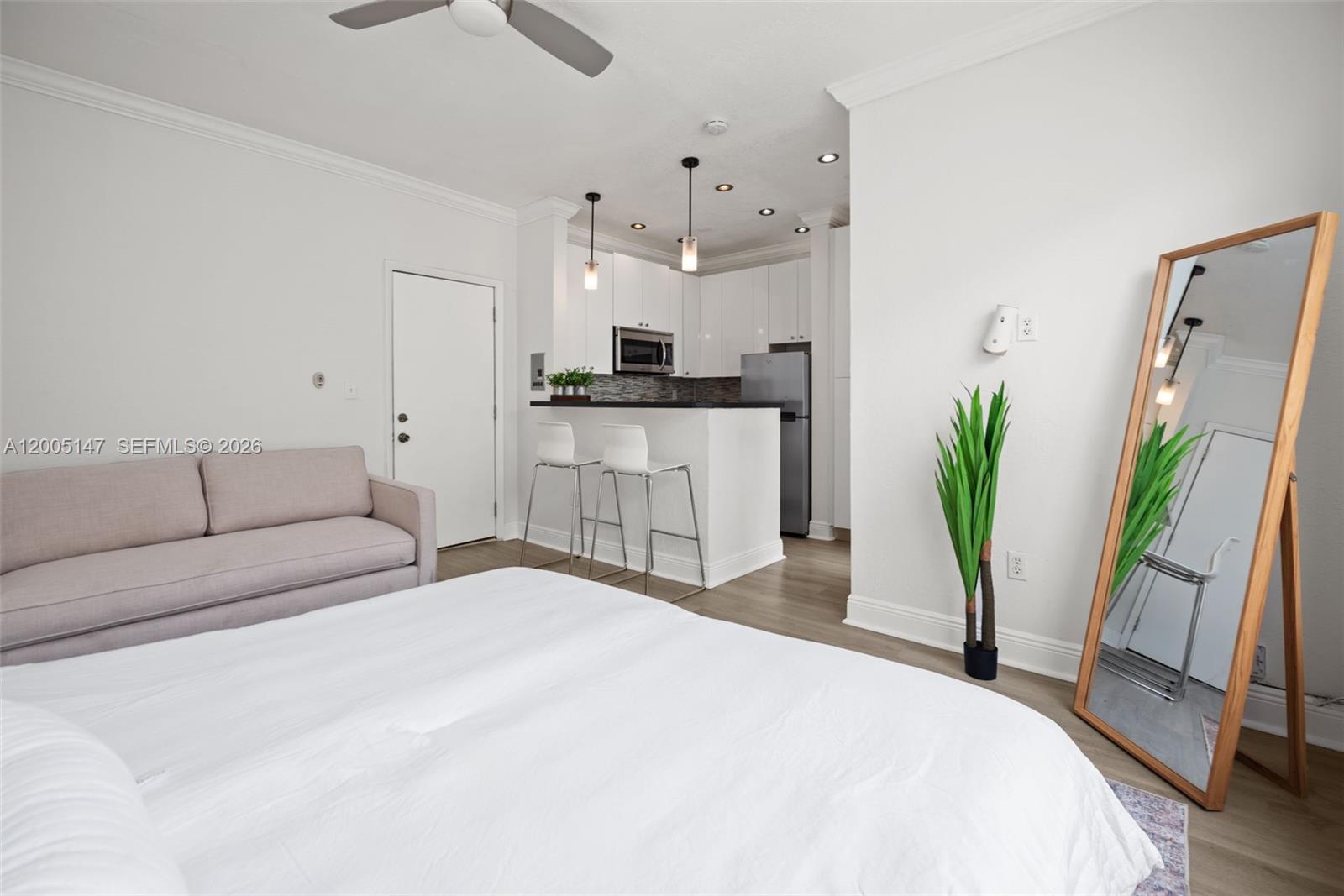 A studio apartment features a bed, sofa, kitchen area with bar seating, and a floor mirror — 119 Menores Ave # 7A, Coral Gables FL 33134, CORAL GABLES, FL