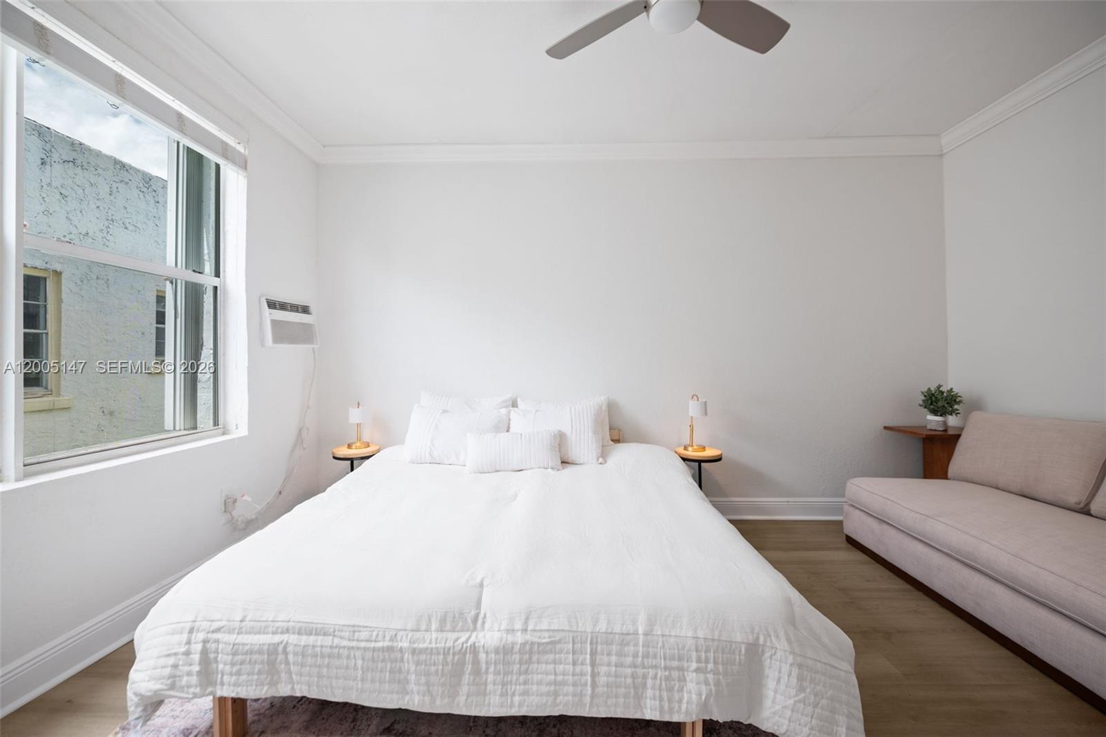 A bedroom features a white bed, two small side tables, and a beige sofa — 119 Menores Ave # 7A, Coral Gables FL 33134, CORAL GABLES, FL