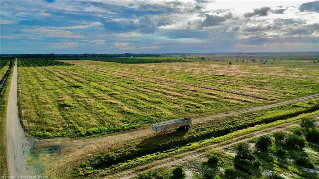 An aerial view shows a large, grassy agricultural field with a trailer parked on a dirt road — 3288 Auburn Street, FL 33857, FL